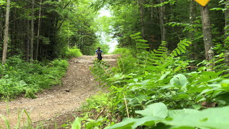 young male adult biking on a gravel road by himself on a summer day