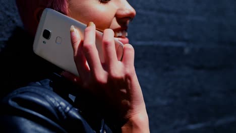 mujer de cabello rosa hablando por teléfono móvil en el callejón 4k