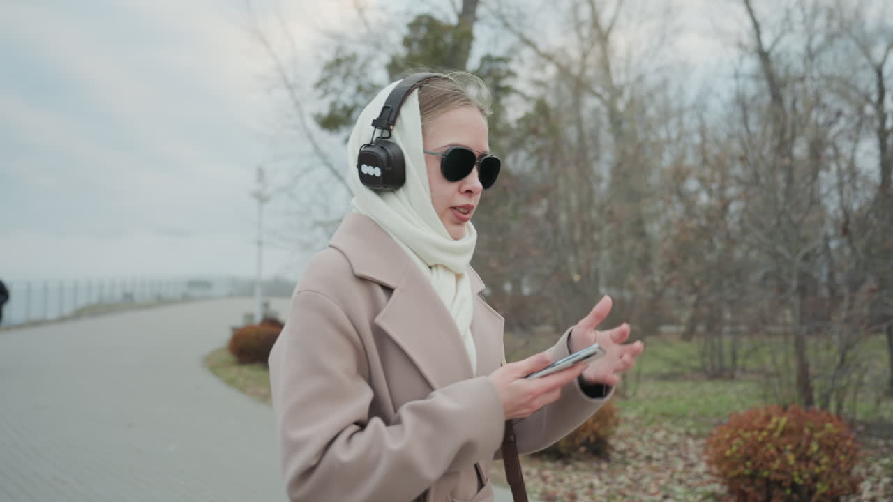 Donna gioiosa che si gode la scena invernale. Donna ascolta pacificamente in un ambiente esterno freddo. Donna solitaria al parco sperimenta la felicità mentre ascolta musica all'aperto in un freddo clima invernale.