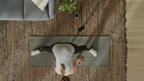 vista superior mujer de yoga ejercitando un estilo de vida saludable estirando el cuerpo flexible disfrutando del entrenamiento en casa practicando atención plena en la colchoneta de ejercicios