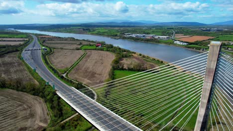 Drohnenansicht-Einer-Hängebrücke-Mit-Einem-Pylon-Mit-Dem-Fluss-Suir-Und-Der-Comeragh-Bergkette-Im-Hintergrund-In-Waterford,-Irland