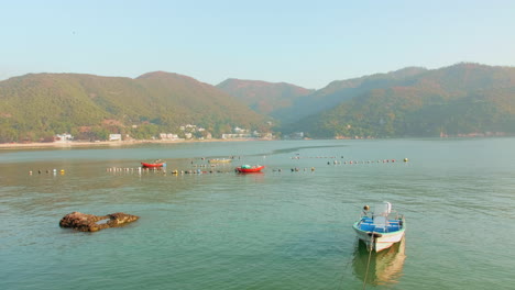 mui wo, silver mine bay (lantau island, hong kong, china). beautiful dreamy landscape with mountains, blue water - sky. small boat near the shore (mui wo ferry pier). peaceful