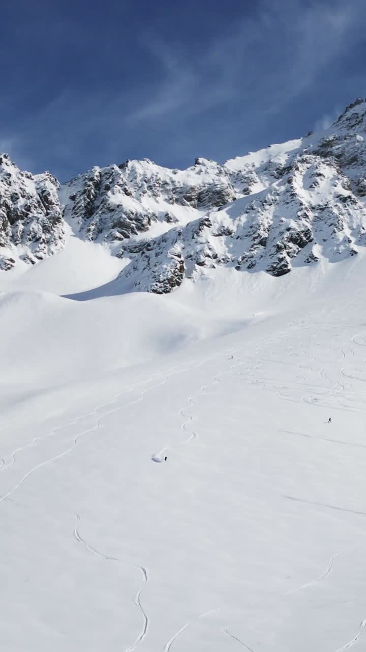 Drone aerial view of a skier skiing in deep powder snow, in a beautiful snowy mountain covered enviroment.