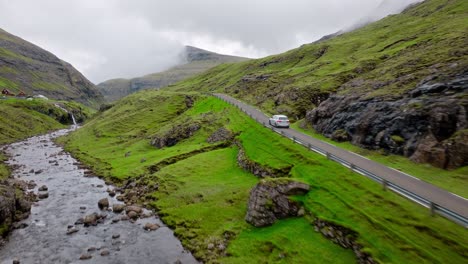 A car driving along a lush green valley in the Faroe Islands, scenic and peaceful