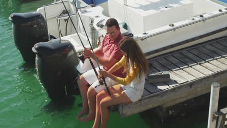 side view of a caucasian man and his teenage daughter fishing harbor side