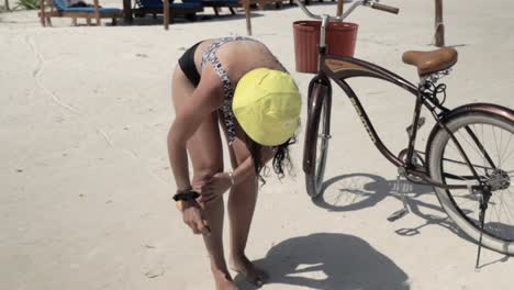 caucasian female applying sunscreen on her skin, with a bicycle in the background