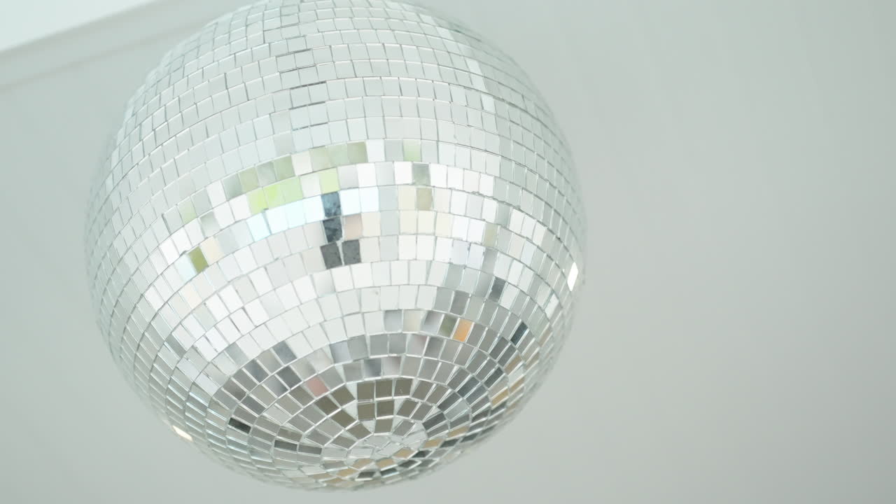 Bola de discoteca colgando del techo, brillando con luz natural.