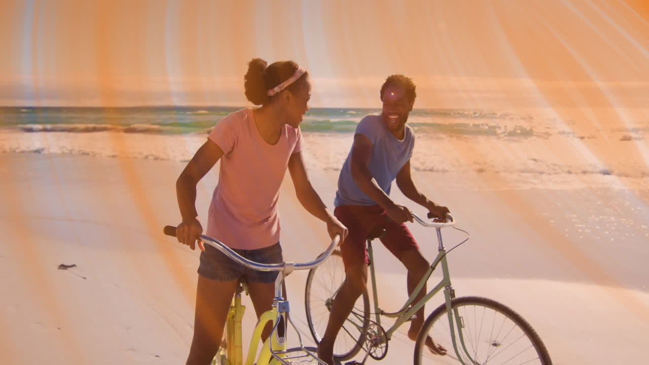 Cycling pastel bicycles along sandy beach, couple showing tech interface with floating charts