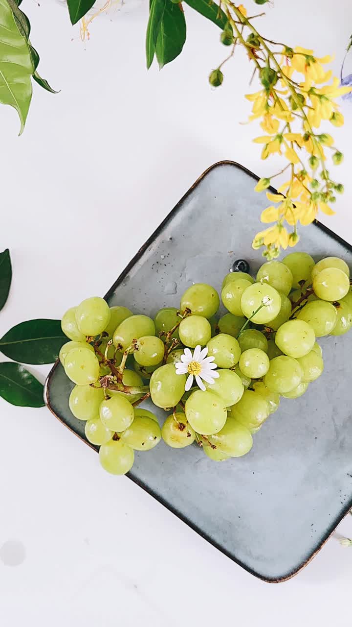 uvas verdes frescas en un plato con arreglo floral