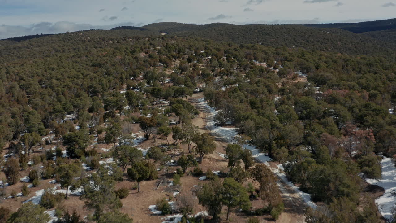 amplia antena moviéndose a baja altura sobre un camino de tierra en un paisaje desértico invernal, 4k