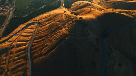 going up over the rolled bare mount with a wavy highway on it. green valley is at the foot of the mountains. top view.