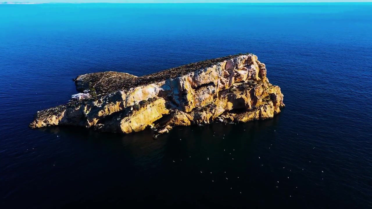 Un piccolo isolotto costiero protetto si erge circondato dalle ampie onde dell'oceano aperto