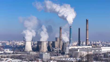 aerial sweep of a coal power plant belching smoke into the upper atmosphere with a sprawling urban landscape in the distance, romania