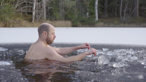 SLOW-MOTION-MS--A-male-ice-bather-sits-down-into-the-icy-water-to-begin