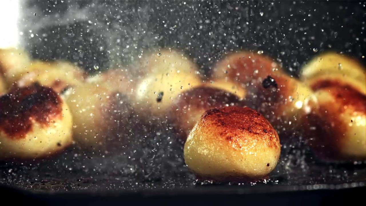 Slow Motion Close-Up of Golden Potatoes Frying and Sizzling in a Hot Pan