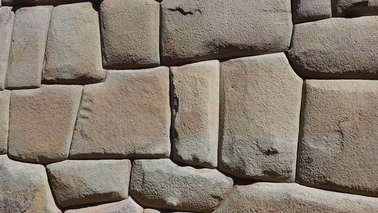 A detailed view of an incredible Inca stone wall in Cusco, Peru. The footage showcases the ancient civilization's masterful stonework and the perfect fitting of each unique stone
