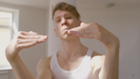 focused young man in casual wear moving hands while performing a contemporary dance in the studio