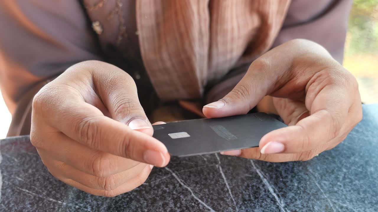 manos de una mujer con una tarjeta de crédito negra