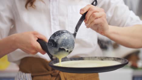 anonymous cook putting the dough for a pancake in the pan