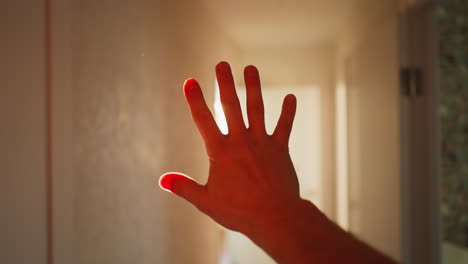 a hand outstretched in front of a doorway bathed in sunlight