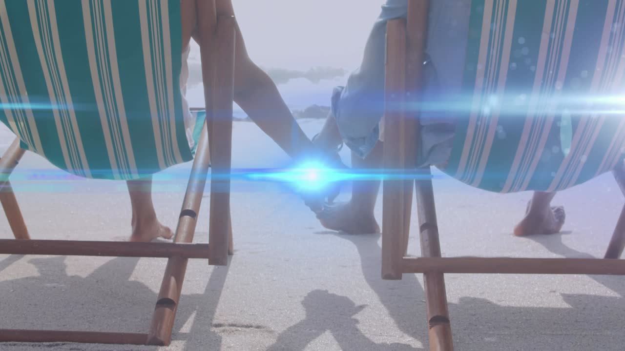 animación de la luz moviéndose sobre una pareja mayor en sillas de playa tomados de la mano
