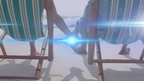 animation of light moving over senior couple on beach deckchairs holding hands