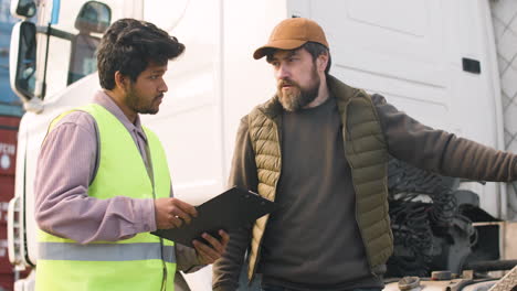 boss and worker organizing a truck fleet in a logistics park while they consulting a document