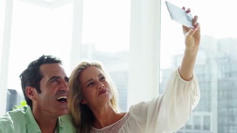 happy couple taking a selfie from mobile phone in living room at home