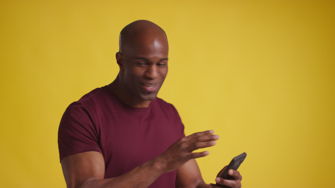 Studio Shot Of Excited Mature Man With Mobile Phone Celebrating Winning Money Against Yellow Background 1