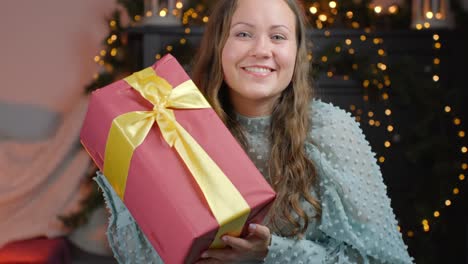 Attraktive-Brünette-Nimmt-Ein-Mit-Goldenem-Band-Verpacktes-Weihnachtsgeschenk-Entgegen,-Pov-ansicht