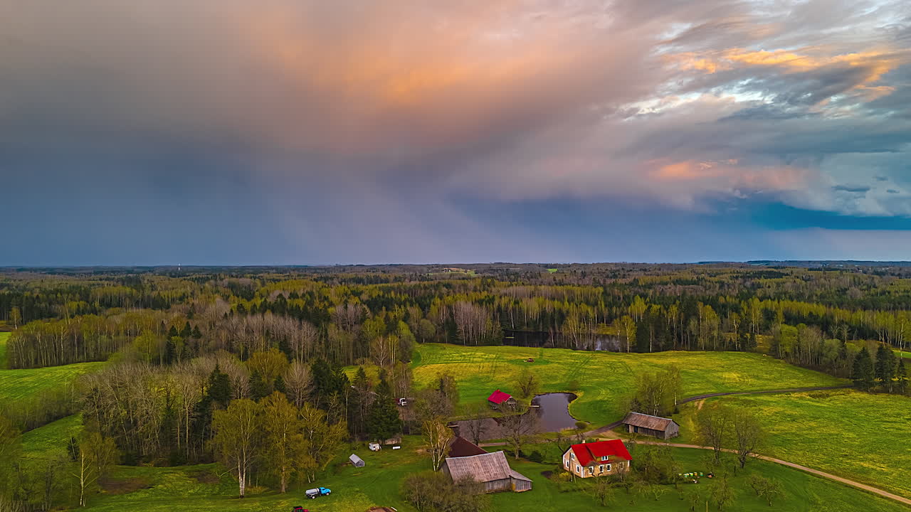 A Tranquil Countryside With Farms, Green Fields, and a Pond Under Dramatic Skies - Timelapse