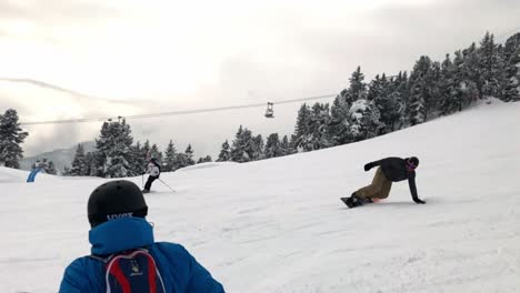 Slow-motion-view-of-person-snowboarding-downhill-in-front-of-other-person