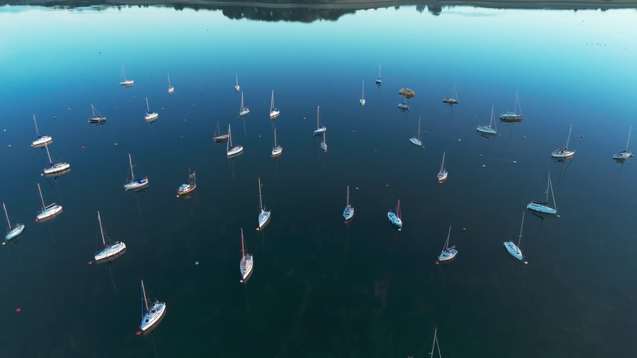Serene sunrise at Rutland Water with fog and moored boats in silence