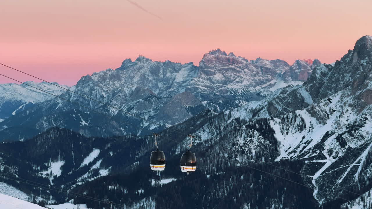 Catena montuosa innevata con funivia al tramonto