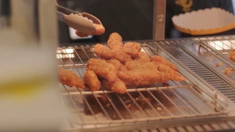 cook takes tongs chicken nuggets from counter