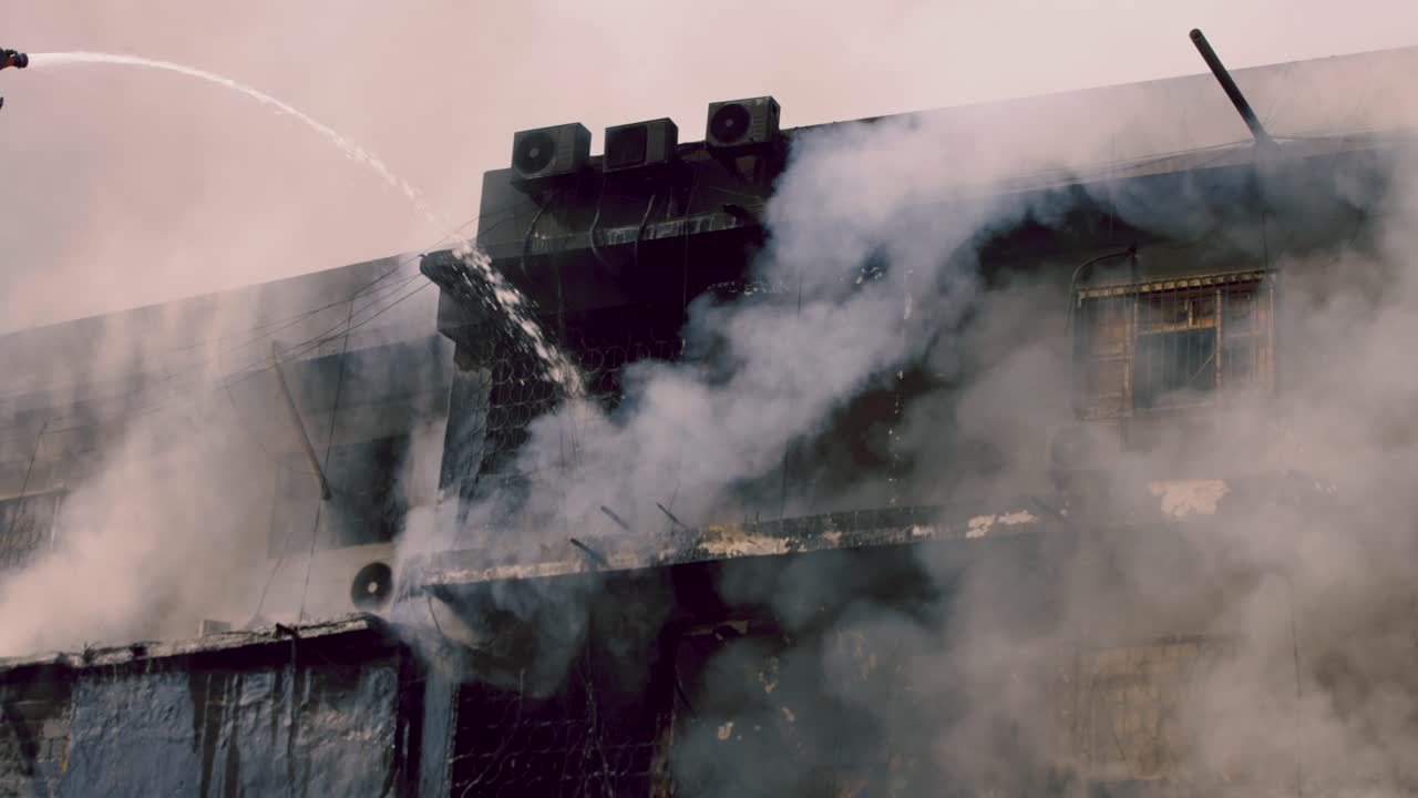 Vigili del fuoco impegnati a domare un vasto incendio al Gul Plaza Shopping Mall, con fumo e acqua che avvolgono l'edificio