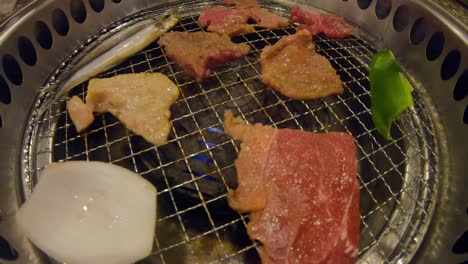 tongs grilling raw meat on yakiniku japanese bbq