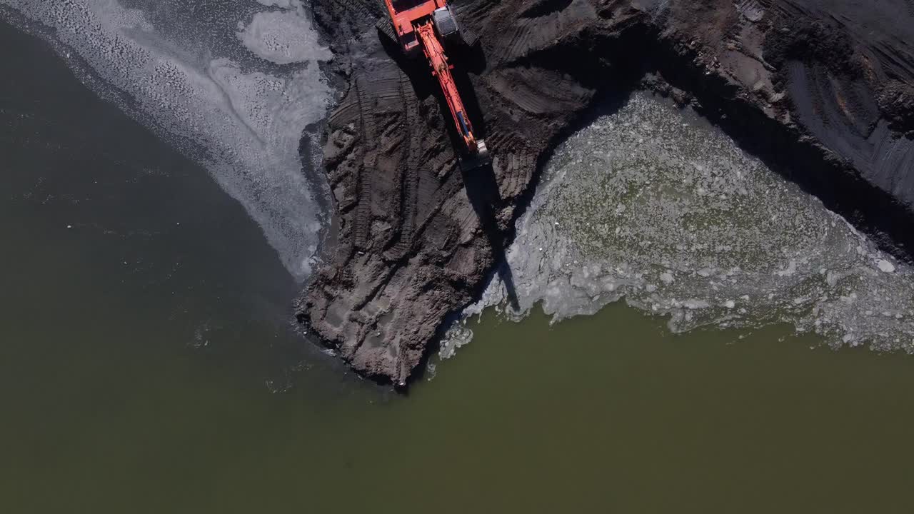 Ripresa aerea dall'alto che mostra macchinari pesanti al lavoro su una sponda fluviale