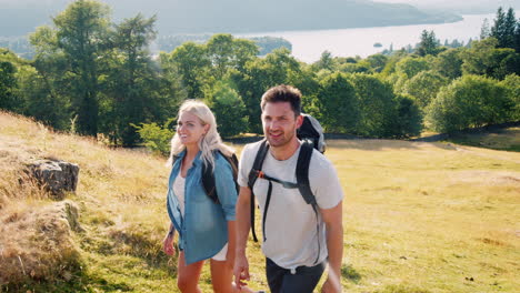 slow motion shot of family climbing hill on hike through countryside in lake district uk together