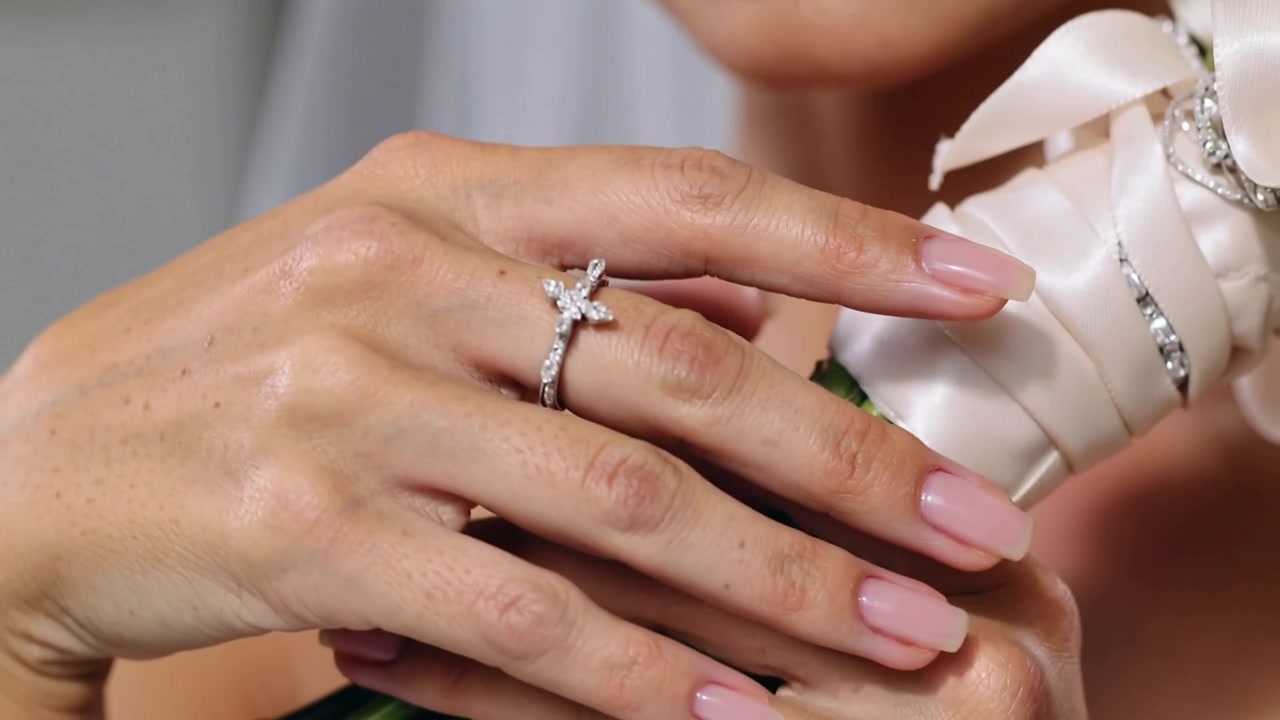 Telecamera che si sposta, sposa velata che sistema il nastro di raso del bouquet nello spogliatoio, mostrando l'anello di diamanti.