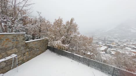 FPV-aerial-flying-over-snow-covered-trees-and-houses-in-the-mountain-landscape-of-Andorra