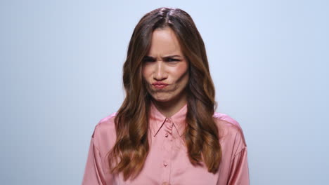 Businesswoman-making-funny-faces-in-studio.-Girl-laughing-on-blue-background