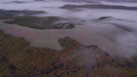 rolling hills of italian countryside with mist during sunrise, aerial