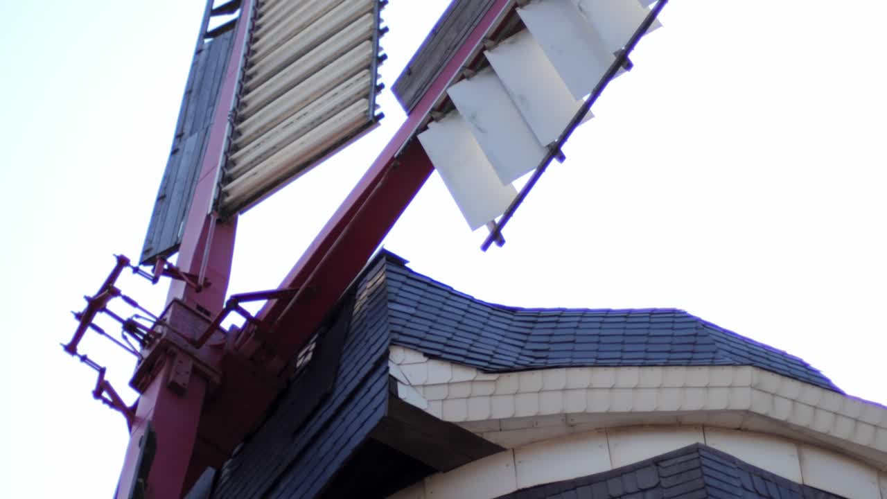 Close up of spinning wheels of an old traditional dutch windmill on a sunny day with a blue sky and the sun. Shot from below upwards.
