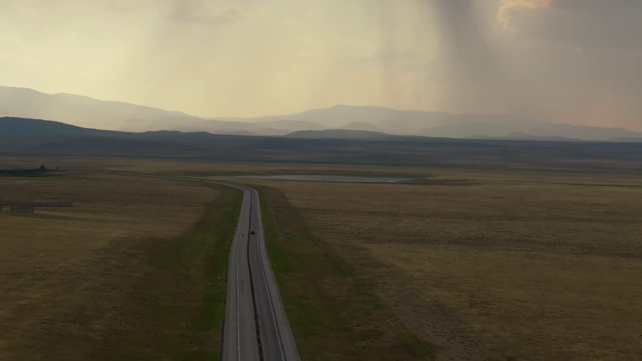 Vast Wyoming road under dramatic sky, solitude and calm travel journey