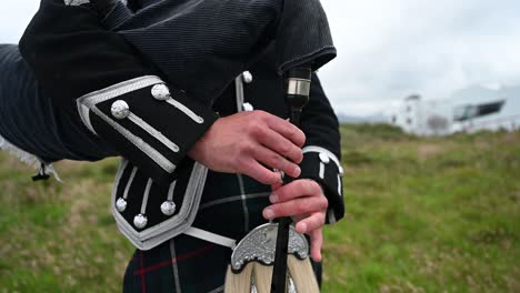 close-up shot of a bagpiper playing a song in his traditional scottish kilt