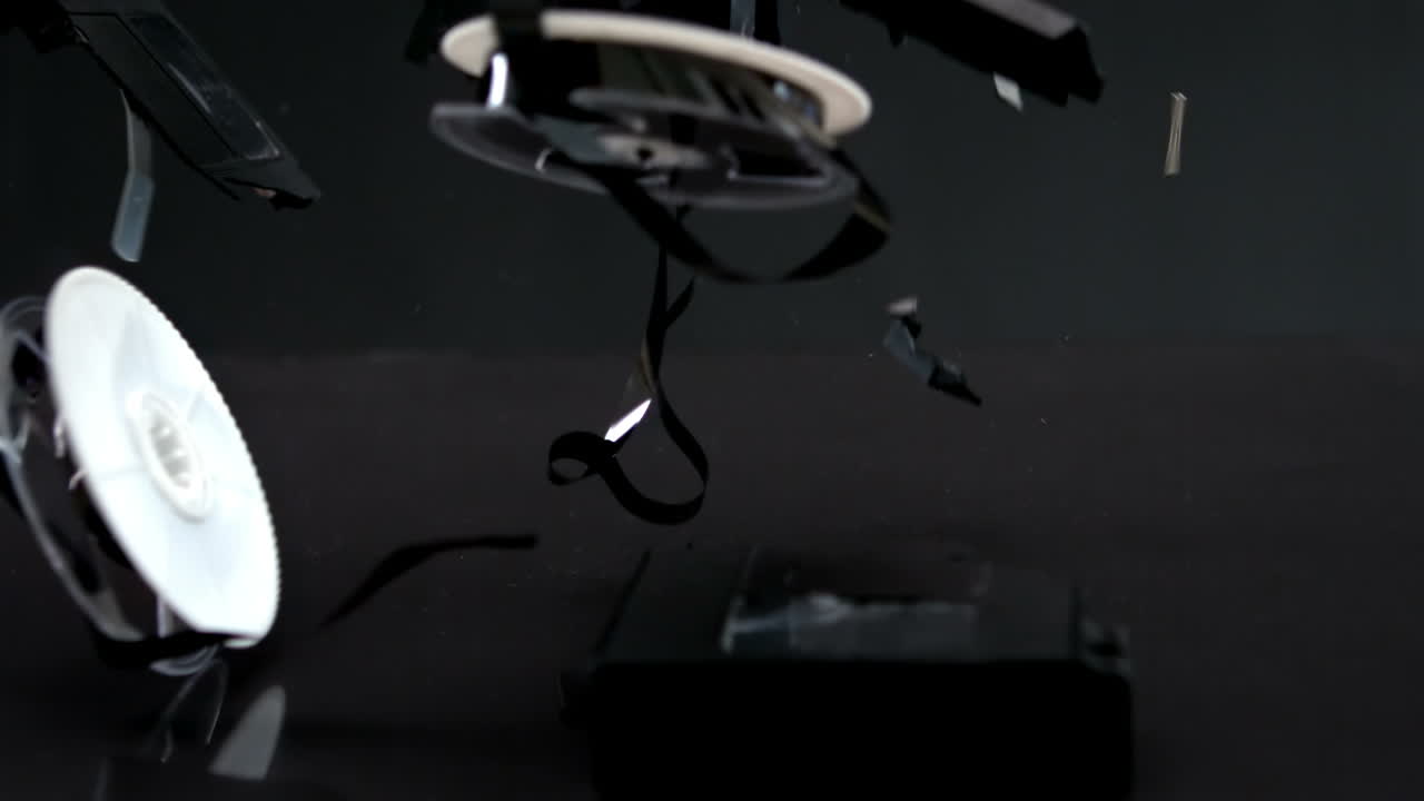 cinta de video cayendo y rompiéndose sobre un fondo negro