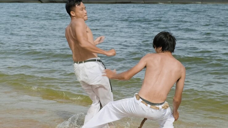 Two men dancing capoeira on the beach