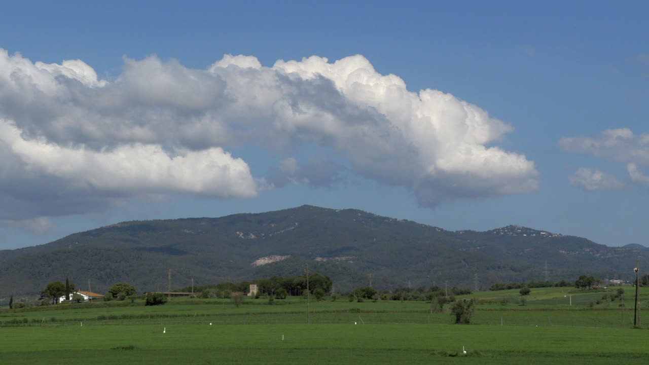 4K Timelapse of cute cloud movement over a mountain and green land in the countryside of Spain