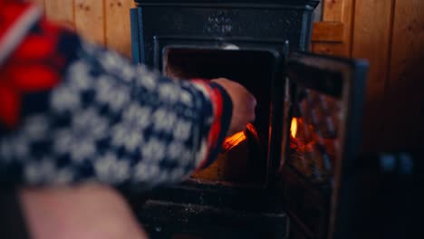 a man starts a fire in a wood-burning stove inside a cabin near reinsjøen in åfjord, trøndelag, norway - close up
